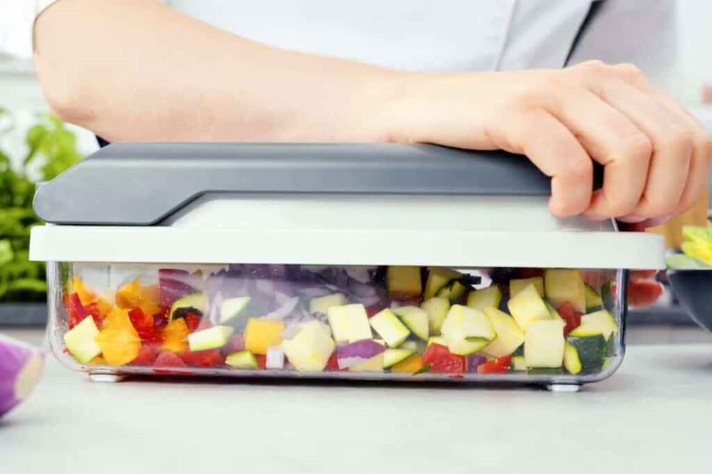 A person is cutting vegetables in a food mandoline slicer