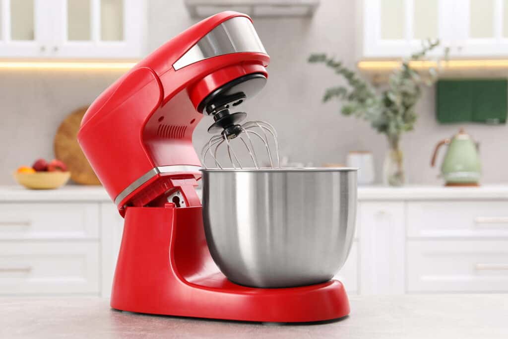 red stand mixer with stainless steel bowl on a kitchen counter